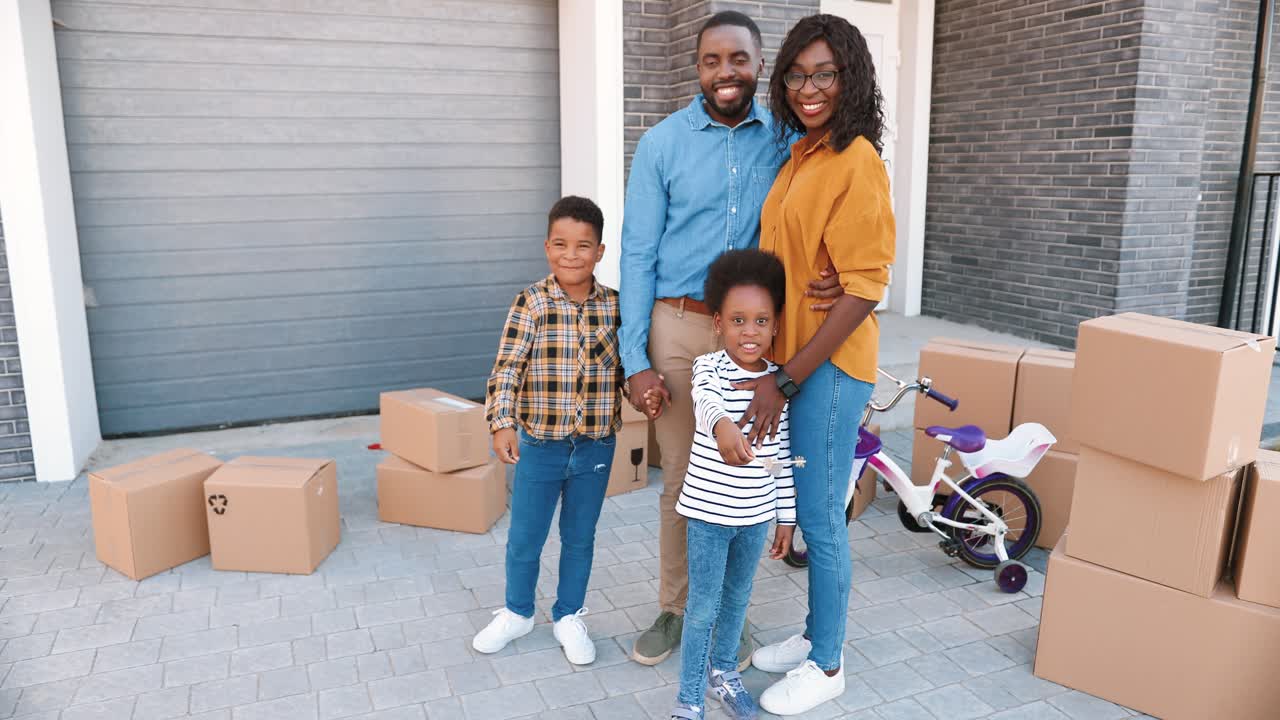 Portrait of happy African American family with small children at new house in suburb smiling