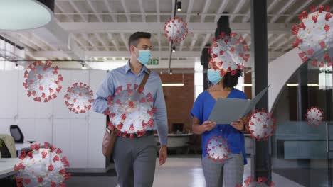 covid-19 cells floating against diverse male and female office colleagues discussing at office