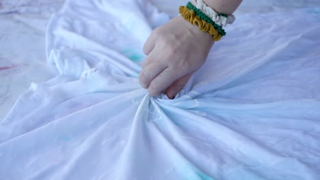 woman applying tie dye technique in t-shirt, wrinkling t-shirt to apply tie dye to clothing