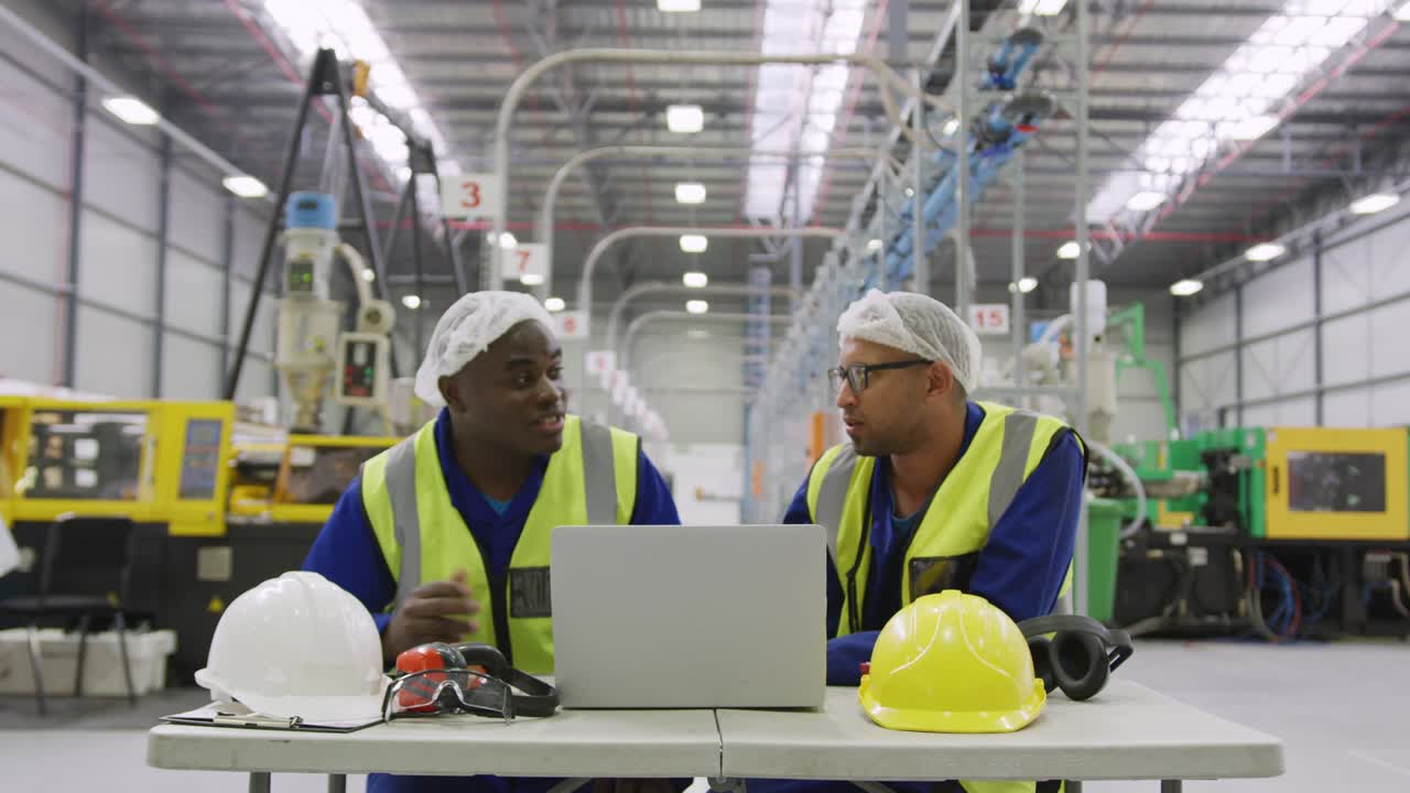 Warehouse workers using laptop in factory