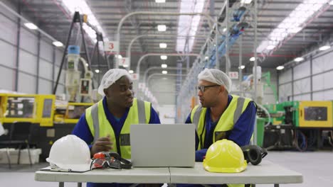 warehouse workers using laptop in factory