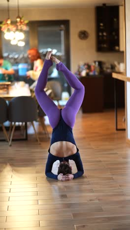 mujer realizando una postura de yoga de pie en la cabeza en casa