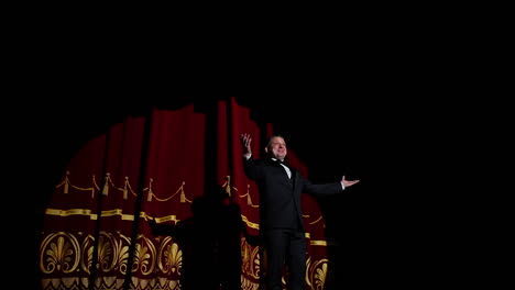 male performer on stage. actor in elegant suit presenting the performance in the theater. comedian appears on the scene. light spot on dark background.