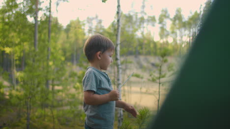 the boy helps his father to set up and assemble a tent in the forest. teaching children and travelling together in a tent camp