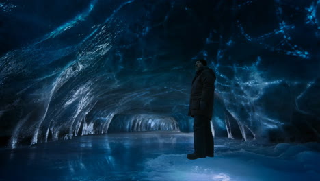person exploring a luminous blue ice cave