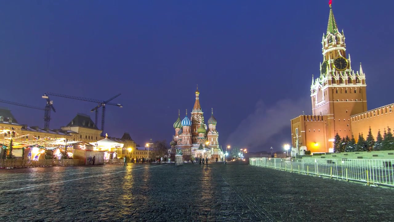 Timelapse de la Place Rouge à Moscou, pendant la transition du jour à la nuit. Le Kremlin de Moscou avec l'emblématique Tour Spasskaïa et la Cathédrale Saint-Basile sont illuminés, créant une scène époustouflante.