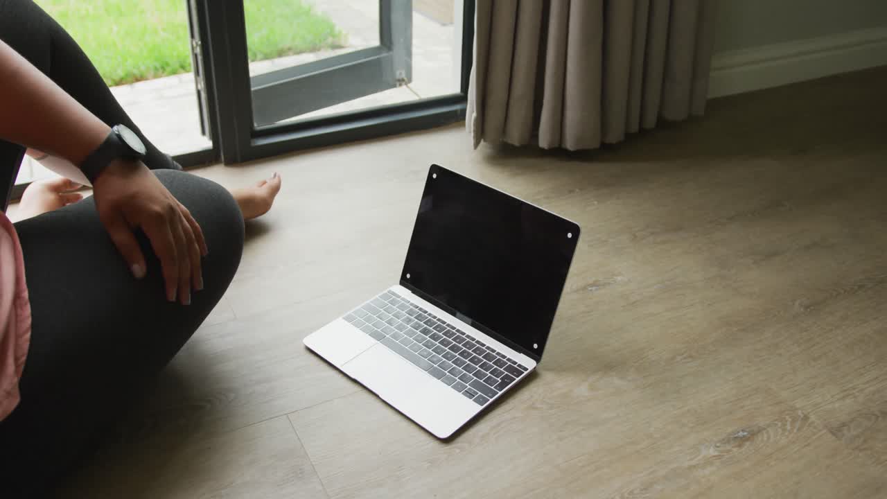 Video di donna afroamericana formosa che pratica yoga con un laptop e spazio per il testo.