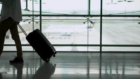 male young passenger walking with suitcase luggage in departure area of airport terminal. asian businessman in casual clothing on business trip. modern travel lifestyle concepts.