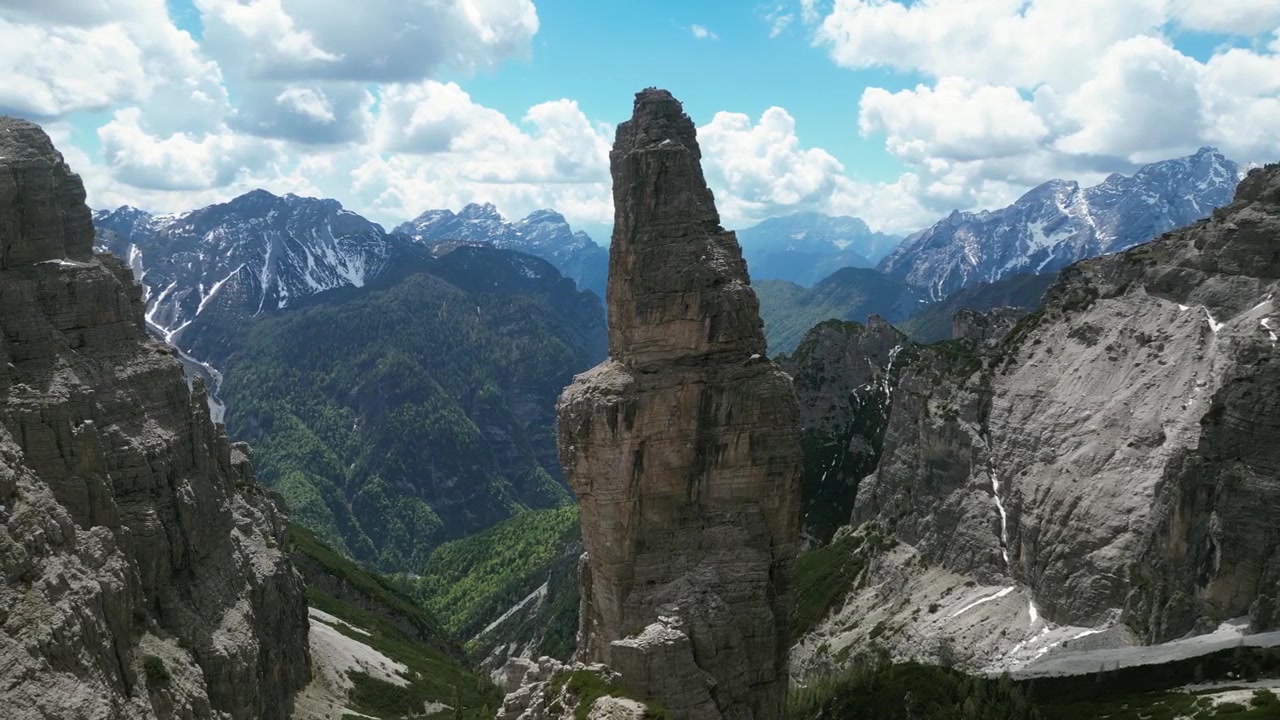 İtalya'daki Campanile di Val Montanaia'nın havadan drone çekimi: Alp vadisinin ve engebeli Dolomit manzarasının üzerinde yükselen dramatik dikey kaya kulesi. Doğa ve macera projeleri için ideal.