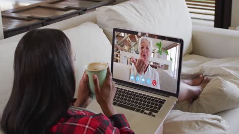 Mixed-race-woman-on-laptop-video-chat-having-coffee-at-home