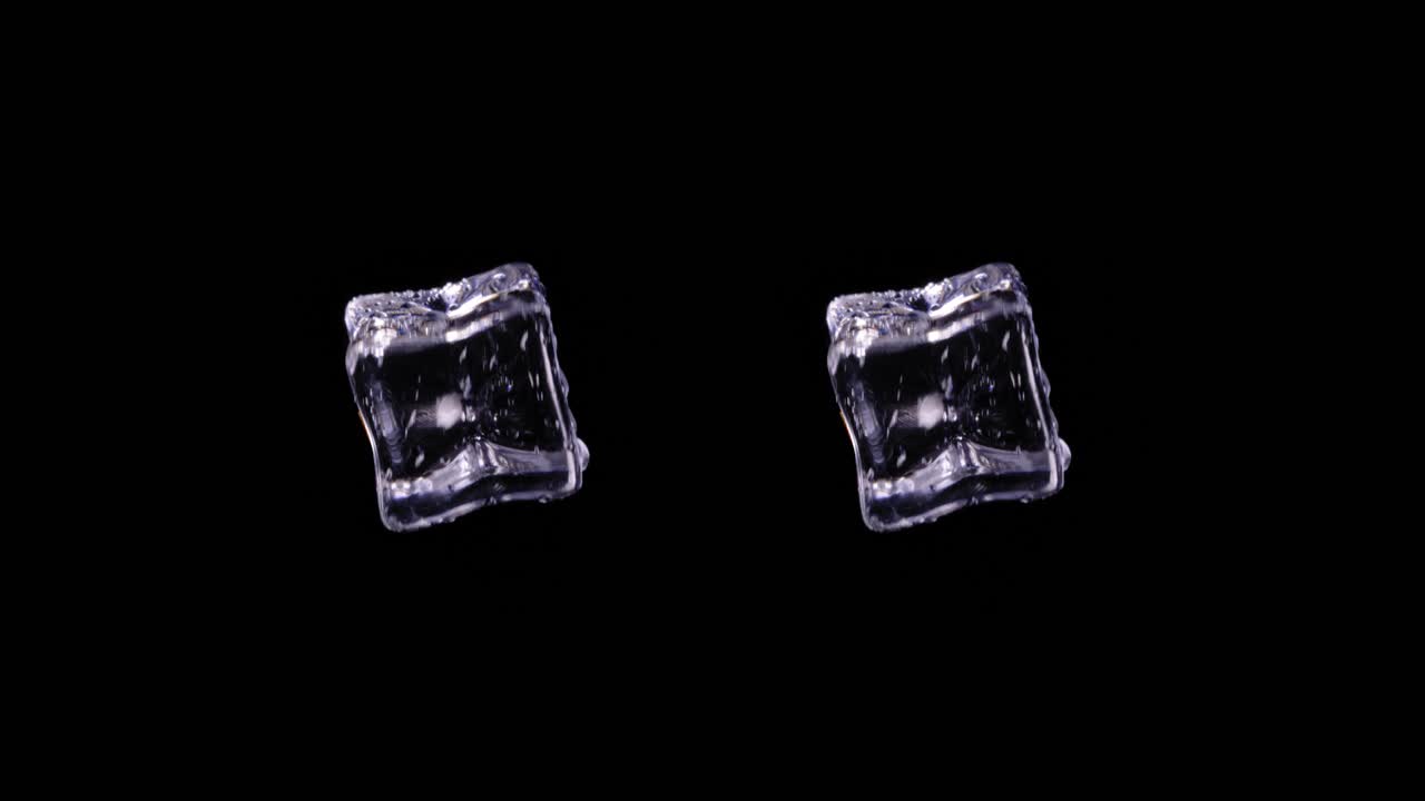 un par de cubos de hielo idénticos girando en el espacio con fondo negro, toma estática de estudio