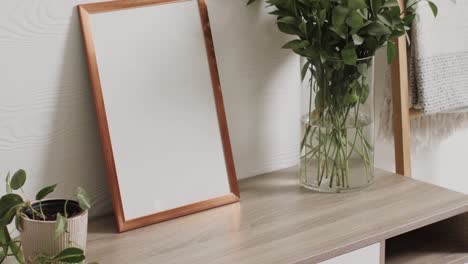 Wooden-frame-with-copy-space-on-white-background-with-plants-on-desk-against-white-wall