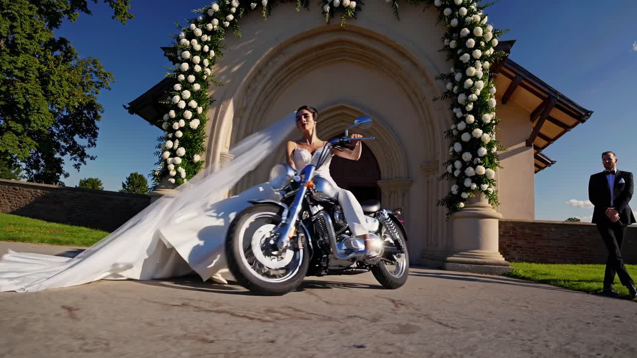 색 의복과 베일을 입은 세련된 신부, 결혼식 후 교회 근처에서 오토바이를 타고, 자유, 모험, 그리고 신랑이 그녀의 도착을 기다리는 현대적인 로맨스를 구현합니다.
