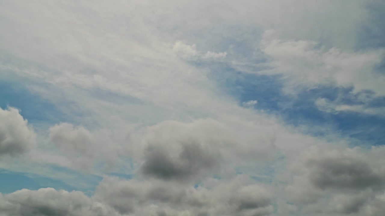 Thick white clouds drift across a bright prairie sky above