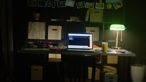 dark home office workspace with laptop and green lamp