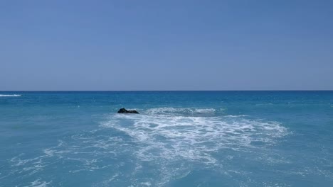 low angle, aerial view of clear turquoise caribbean water as waves break on the beach