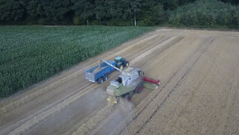 a cinematic 4k drone shot of a combine harvester and a tractor harvesting a field in france, showcasing agriculture with an epic view and dramatic dust