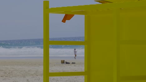 person walking near yellow structure on beach