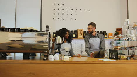 caucasian man with beard and african american young female barista working in modern coffee shop