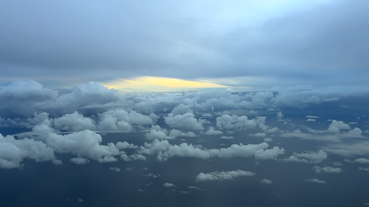 Cockpit view while flying through a stormy sky over the Mediterranean Sea, surrounded by storm cumulonimbus clouds and a few tiny cumulus hanging over the water