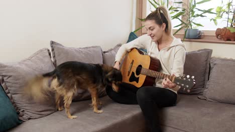 young woman playing guitar while her dog is singing