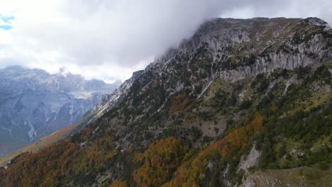 Epic-mountains-in-the-Alps-of-Albania,-clouds-over-high-peaks,-and-colorful-forest-trees