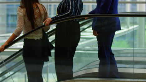 gente de negocios bajando por la escalera mecánica en la oficina 4k