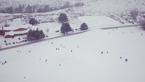 wide aerial shot of kids playing in a large field of snow in america