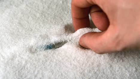 hand lifting syringe out of pile of sugar