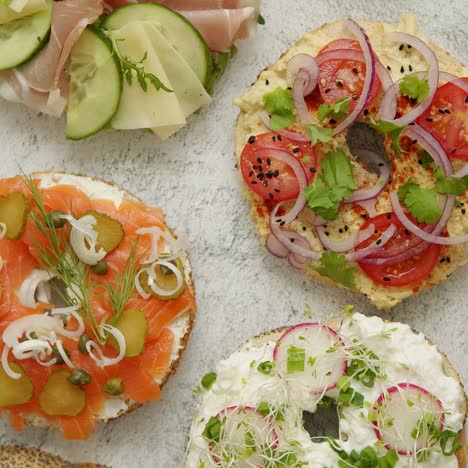 hausgemachte bagel-sandwiches mit verschiedenen toppings lachs-hüttenkäse-hummus-schinken-rettich