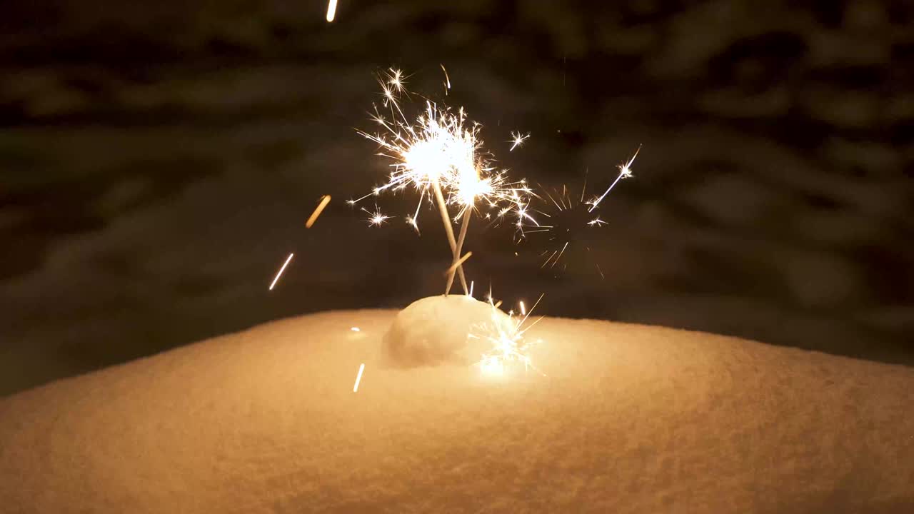 Sparklers placed in the snow. Bright sparkles of sparklers in the dark.