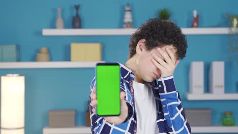 Unsuccessful-young-man-turns-the-phone-to-the-camera.-Green-screen.