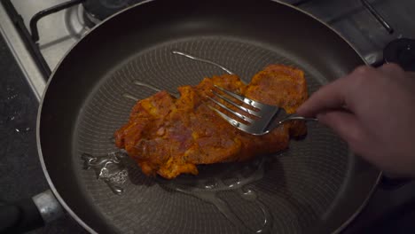 Marinated-beef-chuck-steak-is-placed-into-fry-pan-on-top-of-gas-stove