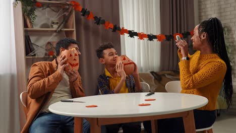 family celebrating halloween by carving pumpkins together