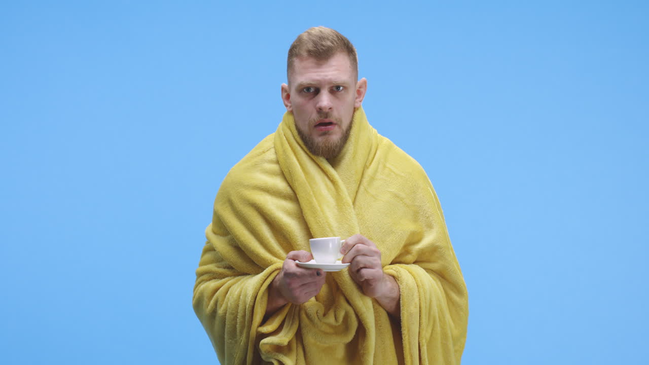 Man Wrapped in a Blanket Drinking Coffee