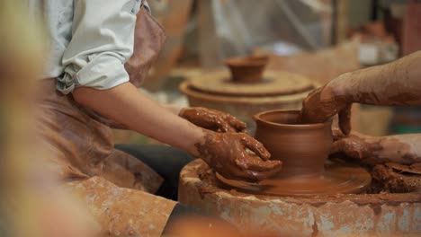 pottery classes, woman making clay pot on wheel. close-up of dirty hands, sculpting clay crockery masterclass pottery training