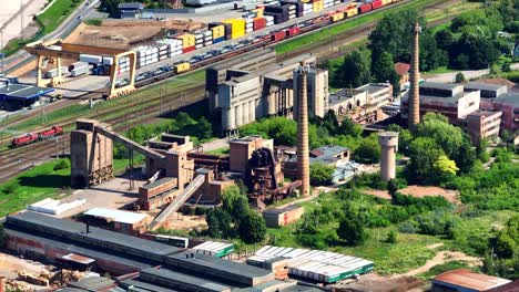 aerial view abandoned factory, production buildings and warehouses, and tall chimneys stand by the railway tracks