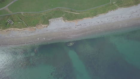 Fly-up-and-away-from-underwater-rocks-to-reveal-the-beach