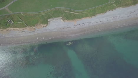 vuela hacia arriba y lejos de las rocas submarinas para revelar la playa