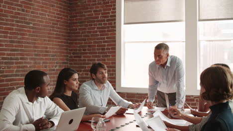 mature businessman standing to address boardroom meeting