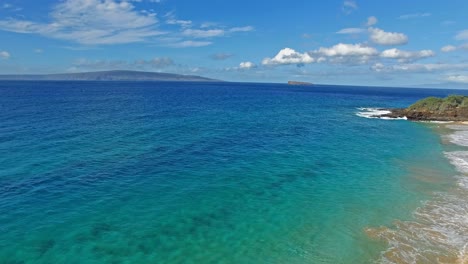 toma aérea panorámica sobre agua azul clara en hawai con tierra en el fondo