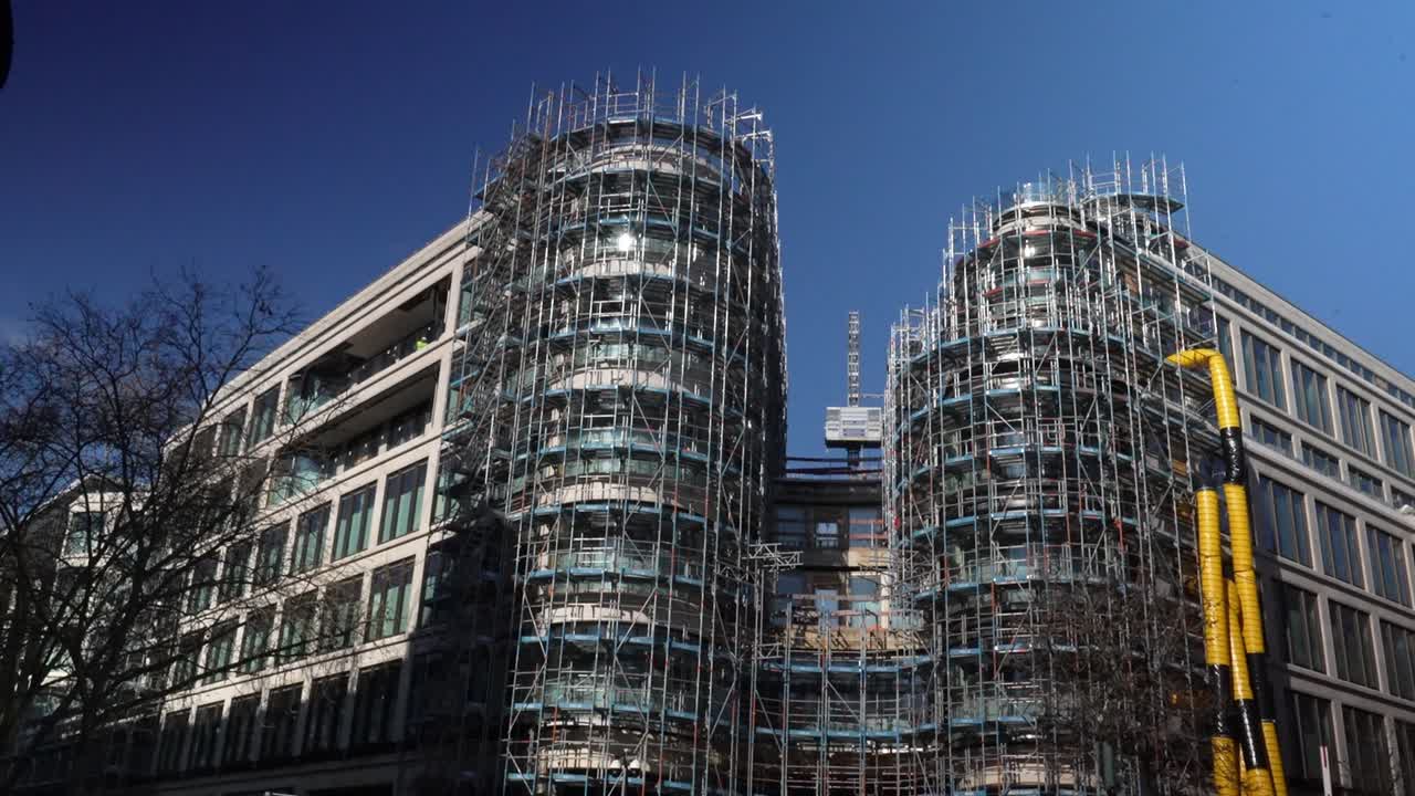 Modern office building under construction with extensive scaffolding structure in urban city environment in Düsseldorf Germany showing renovation and development work