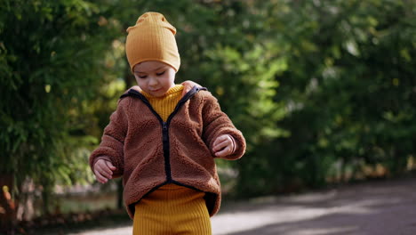 lovely caucasian boy picks up chestnuts from the floor. toddler having fun in autumn outdoors.
