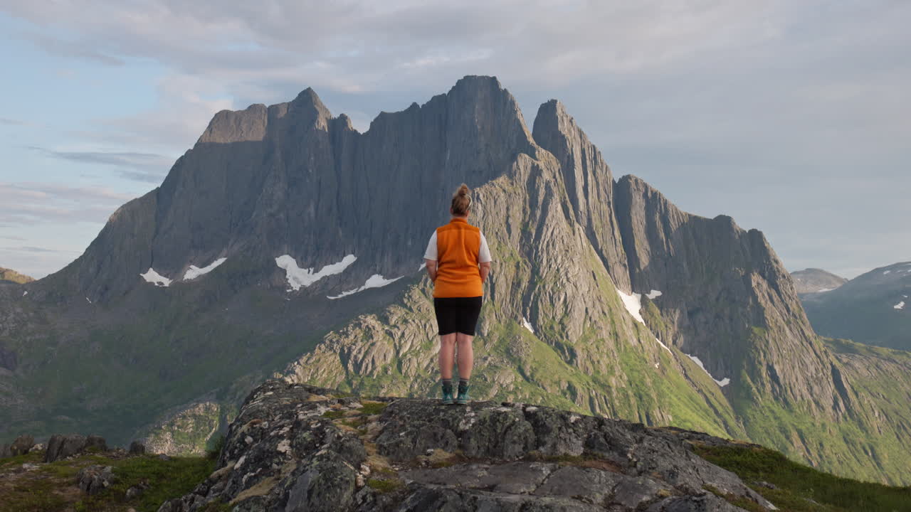 Back of female hiker in front of majestic jagged arctic Norway mountain