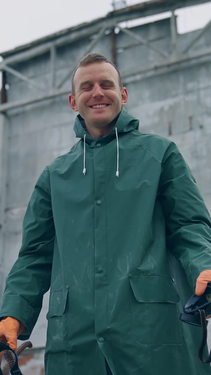 Happy ecologist in abandoned place. Man survivor holding gas mask in hands and smiles breathing fresh air on the background of destroyed building. Vertical video