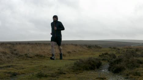 runner keeping healthy running past camera training for marathon in cold conditions in moorland countryside uk 4k