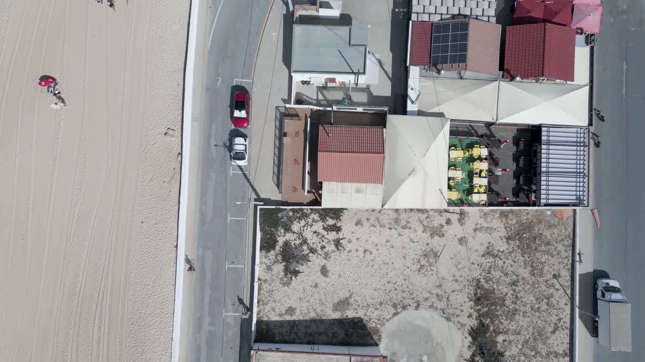 la vista aérea sigue la dirección de una carretera, revelando casas en faro cerca de la playa, capturando la perspectiva escénica de la zona costera desde arriba