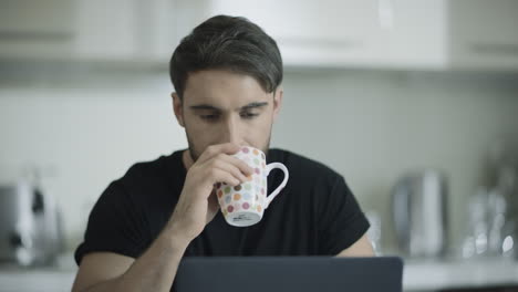 hombre serio bebiendo café trabajando en casa. hombre de negocios enfocado trabajando en una computadora portátil