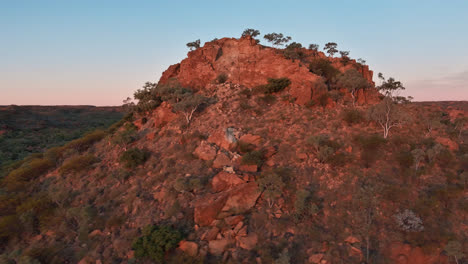 Drone-shot-circling-around-a-natural-rock-formation-with-red-dusty-soil-at-dusk-in-Mount-Isa,-Queensland,-Australia