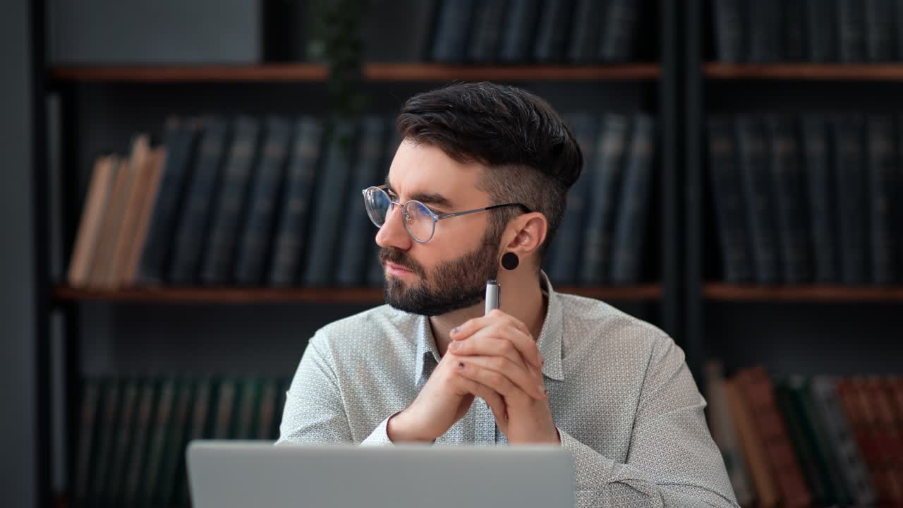 Pensive bearded business man student teacher working at library thinking planning use laptop